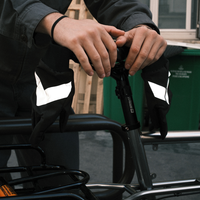 Deux mains gantées ajustant la tige de selle d'un vélo, lanières anti-perte et flèches réfléchissantes visibles